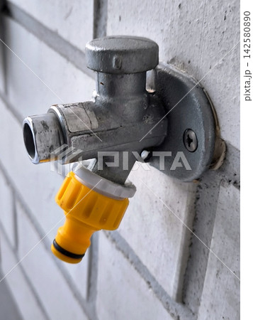 Wall-mounted metal outdoor tap with an adapter and a bright yellow quick-connect fitting for a garden hose. 142580890