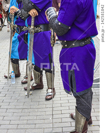 Participants in medieval style costumes display swords during a gathering at a public event 142581842