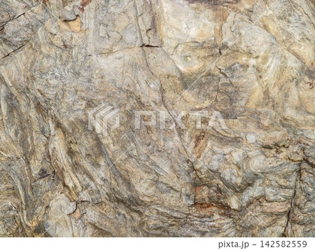 rock surface static in natural rugged outdoor environment close-up perspective with gray brown tan beige colors and igneous rock material for backgrounds construction materials. rock surface static in natural rugged outdoor environment close-up perspective with gray brown tan beige colors and igneous rock material for backgrounds construction materials. 142582559