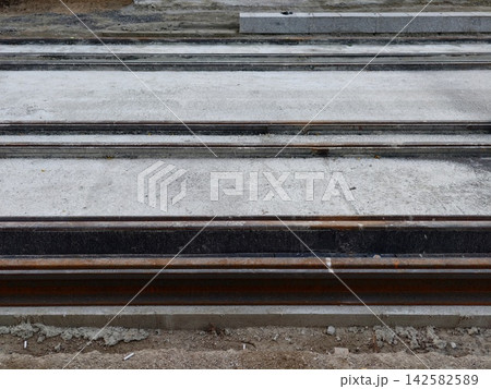 stationary railroad tracks in an urban environment with a ground-level perspective and neutral mood, featuring concrete bases and dirt surroundings, construction and urban design. stationary railroad tracks in an urban environment with a ground-level perspective and neutral mood, featuring concrete bases and dirt surroundings, construction and urban design. 142582589