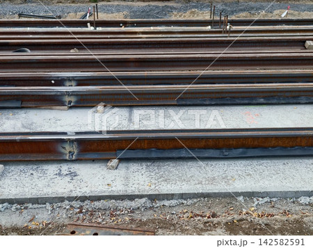 construction site with railroad tracks under development, concrete sleepers and steel materials visible, industrial ground-level perspective, gray and brown tones. construction site with railroad tracks under development, concrete sleepers and steel materials visible, industrial ground-level perspective, gray and brown tones. 142582591