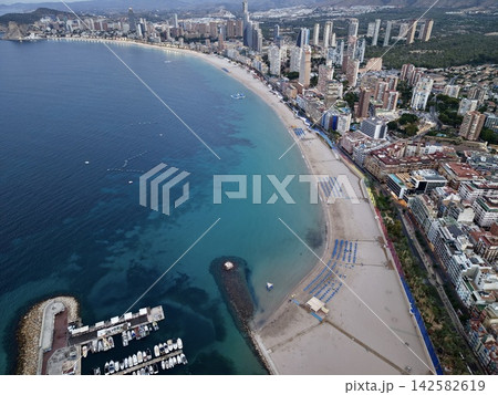 tranquil aerial view of high-rise beachfront cityscape with palm trees and boats in marina, urban development setting, blue and tan tones, clean concrete and glass materials, modern design. tranquil aerial view of high-rise beachfront cityscape with palm trees and boats in marina, urban development setting, blue and tan tones, clean concrete and glass materials, modern design. 142582619