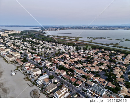 peaceful coastal town with residential buildings and wetlands near a body of water, serene aerial view of tranquil real estate area for vacation rentals and tourism. peaceful coastal town with residential buildings and wetlands near a body of water, serene aerial view of tranquil real estate area for vacation rentals and tourism. 142582636