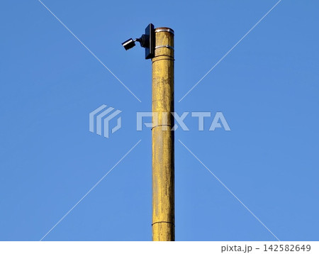 tall yellow pole with security camera against clear blue sky in top-down perspective for industrial security and urban infrastructure use cases, neutral mood, clean background. tall yellow pole with security camera against clear blue sky in top-down perspective for industrial security and urban infrastructure use cases, neutral mood, clean background. 142582649