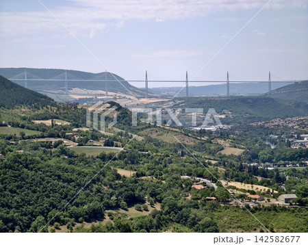 millau viaduct spanning valley rural landscape with hills and fields concrete steel aerial perspective serene expansive green brown natural light clean background copy space editorial use. 142582677