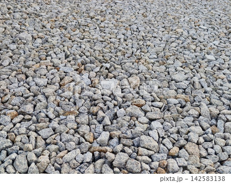 Close up view of gray gravel stones covering rugged ground surface with angular crushed rock texture and coarse pebbles, with rock, gravel, stone, pebble detail Close up view of gray gravel stones covering rugged ground surface with angular crushed rock texture and coarse pebbles, with rock, gravel, stone, pebble detail 142583138