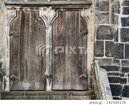 Weathered wooden entrance gates surrounded by mosscovered stone steps and tactile surface textures 142584176