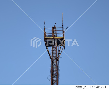 Focused scene of technician inspecting utility tower at great height with safety precautions 142584221