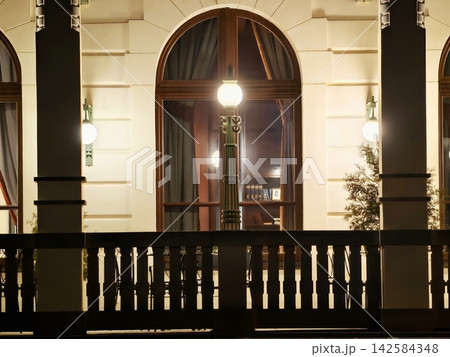Warm glow on glass surface. Serene scene of nighttime window with soft drapes and warm illumination Warm glow on glass surface. Serene scene of nighttime window with soft drapes and warm illumination 142584348