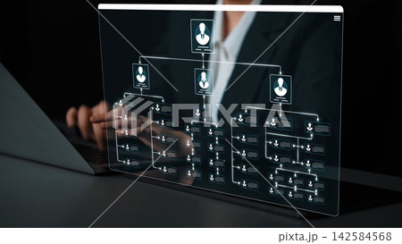 A businesswoman works on a laptop displaying a transparent organizational chart, demonstrating modern technology and data visualization in a professional office setting. Sigmoid 142584568
