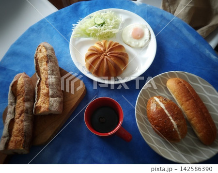 バラエティ豊かなパンと目玉焼きサラダ、コーヒーの朝食セット バラエティ豊かなパンと目玉焼きサラダ、コーヒーの朝食セット 142586390