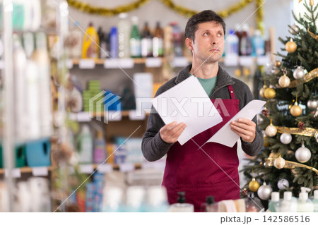 Bewildered man seller work with document, looks at report and is upset by results of stores work Bewildered man seller work with document, looks at report and is upset by results of stores work 142586516
