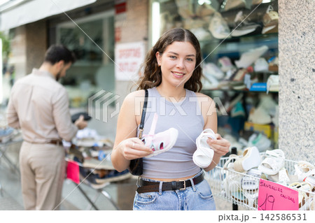 Young woman chooses baby shoes for her unborn child at a street shoe market. Shoes for child 142586531