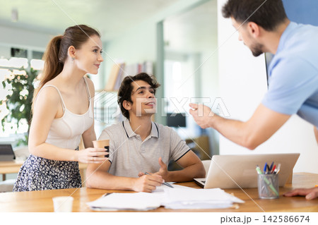 Girl and two men office staff talk and discuss working issues, discuss document papers 142586674