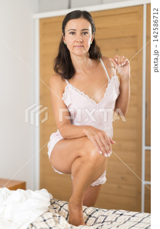 Woman posing in nightgown lying on bed in bedroom 142586712