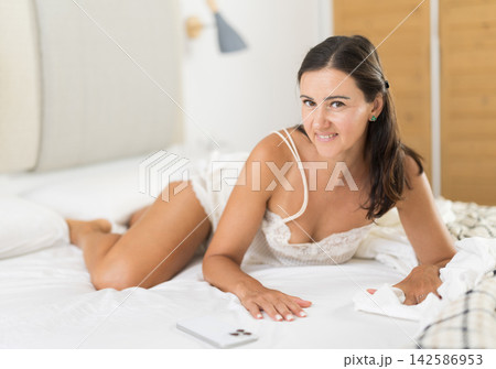 Adult woman posing on bed in bedroom Adult woman posing on bed in bedroom 142586953