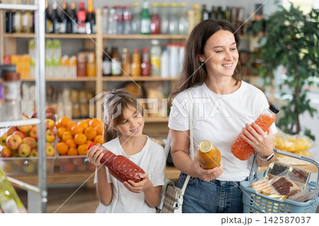 Child girl with mother choose consider juice Child girl with mother choose consider juice 142587037