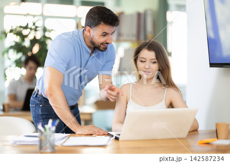 Young man helping female colleague with tasks on laptop Young man helping female colleague with tasks on laptop 142587234