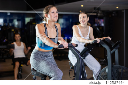 During classes on air bike, girls chat sweetly and smile 142587464
