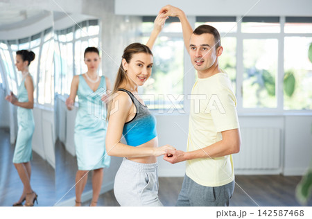 Couple in comfortable sports clothes waltz dancing during individual lesson Couple in comfortable sports clothes waltz dancing during individual lesson 142587468