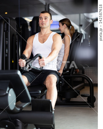 Man pulls handle of simulator with effort during strength training. 142587618