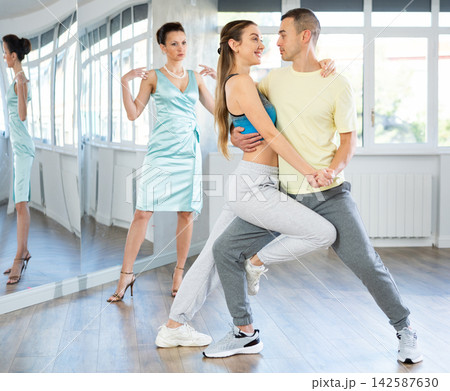 Couple rehearsing elegant tango under guidance of female teacher Couple rehearsing elegant tango under guidance of female teacher 142587630