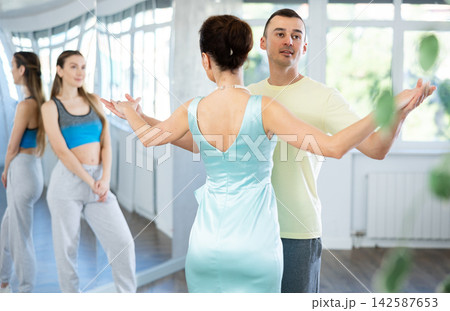 Coach, paired with man student, shows master class and explains technique of waltz dance 142587653