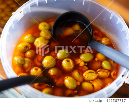 Pile of pitted green olives in bucket 142587717
