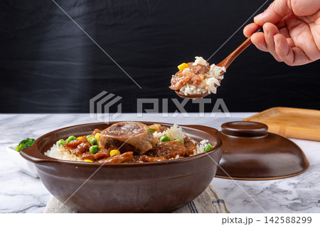 Chinese combo claypot rice with sliced beef and savory cured duck, spoon scooping rice meal 142588299