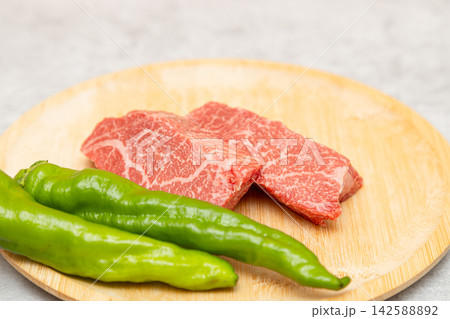 鹿児島県産の黒毛和牛のもも肉ステーキ用 辛くないしし唐の甘唐辛子が添えられている 鹿児島県産の黒毛和牛のもも肉ステーキ用 辛くないしし唐の甘唐辛子が添えられている 142588892