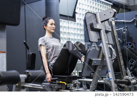 スポーツジムでトレーニングする若い女性　レッグプレス 142590473