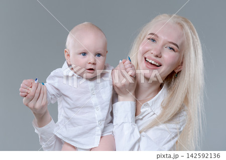 Laughing Young Mother and Her Happy Baby Boy in Studio Laughing Young Mother and Her Happy Baby Boy in Studio 142592136