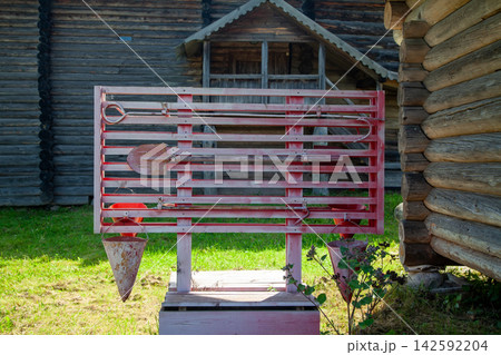 Outdoor fire safety board with buckets, axe, hook, and fire extinguisher near wooden village houses Outdoor fire safety board with buckets, axe, hook, and fire extinguisher near wooden village houses 142592204