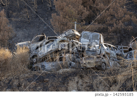 Burned abandoned cars piled in scorched hillside aftermath landscape Burned abandoned cars piled in scorched hillside aftermath landscape 142593185