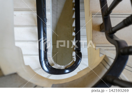 Top view of a spiral staircase with classic handrails, showcasing architectural design and symmetry. 142593269