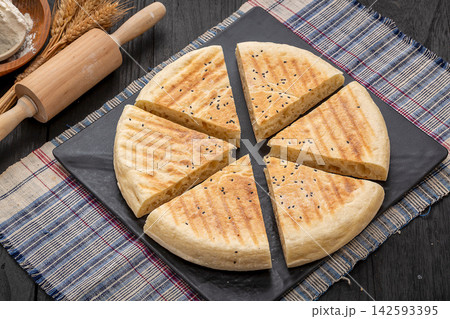 authentic Xinyang thick flatbread with a cut slice, crispy grilled Chinese wheat bread on a black platter. 142593395