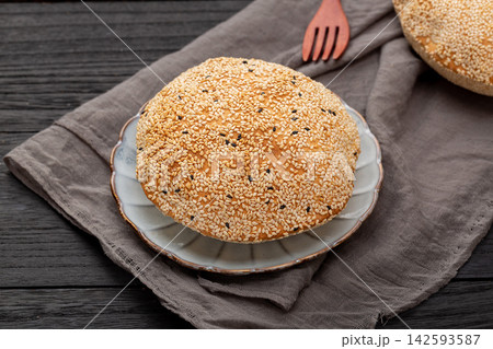 crispy Chinese hollow sesame flatbread, traditional baked pastry pocket on a plate. crispy Chinese hollow sesame flatbread, traditional baked pastry pocket on a plate. 142593587