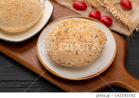 crispy Chinese hollow sesame flatbread, traditional baked pastry pocket on a plate. crispy Chinese hollow sesame flatbread, traditional baked pastry pocket on a plate. 142593592