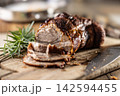 Tasty roasted pork neck with a crispy crust is garnished with fresh rosemary and sliced on a wooden board. This professional culinary shot will fit perfectly in cookbooks, restaurant menus, or food 142594455