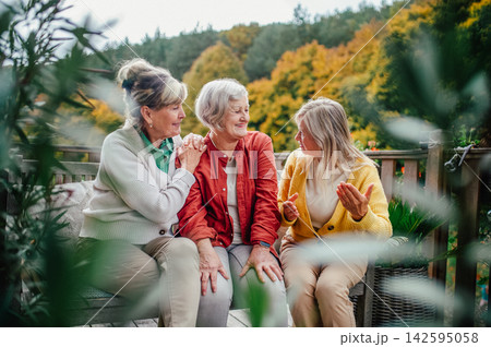 Three senior women enjoying peaceful autumn afternoon outdoors. Three senior women enjoying peaceful autumn afternoon outdoors. 142595058