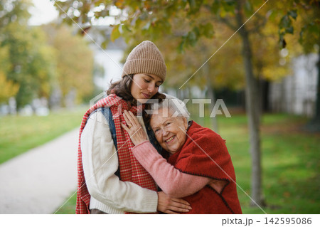 Portrait of a granddaughter on an autumn walk in the park with her grandmother. Portrait of a granddaughter on an autumn walk in the park with her grandmother. 142595086