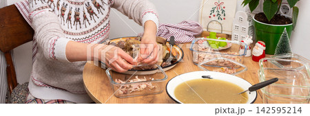 In a cozy home setting, a woman prepares kholodets, aspic, or jellied meat, traditional Ukraine dish, by packing cooked meat into glass dishes 142595214