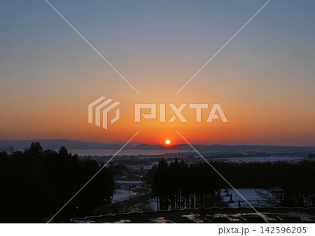 冬の夕暮れ時、オレンジ色に輝く夕日と地平線。白い雪原とのコントラストが印象的で綺麗だ。 冬の夕暮れ時、オレンジ色に輝く夕日と地平線。白い雪原とのコントラストが印象的で綺麗だ。 142596205