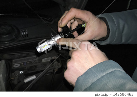 Xenon lamp in hands of an electrician. Replacing xenon lamps. Xenon lamp in hands of an electrician. Replacing xenon lamps. 142596463