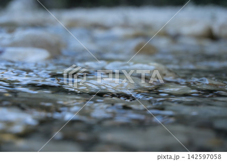 Abstract close up of clear water flowing over rounded pebbles in a mountain stream 142597058