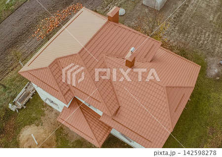 House with an orange metal roof. Corrugated metal roof and metal roofing. Modern roof made of metal. House with an orange metal roof. Corrugated metal roof and metal roofing. Modern roof made of metal. 142598278