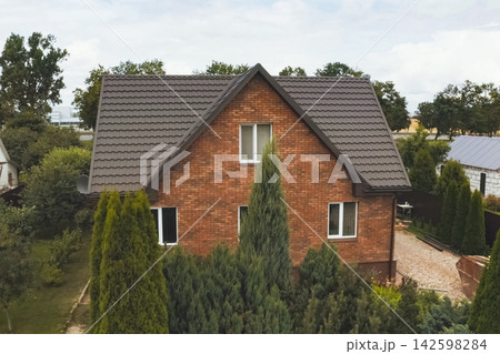 House with a brown metal roof.Corrugated metal roof and metal roofing. Modern roof made of metal. House with a brown metal roof.Corrugated metal roof and metal roofing. Modern roof made of metal. 142598284