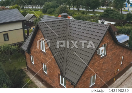 House with a brown metal roof.Corrugated metal roof and metal roofing. Modern roof made of metal. House with a brown metal roof.Corrugated metal roof and metal roofing. Modern roof made of metal. 142598289