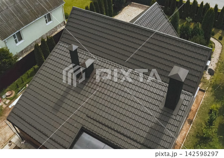 House with a brown metal roof.Corrugated metal roof and metal roofing. Modern roof made of metal. House with a brown metal roof.Corrugated metal roof and metal roofing. Modern roof made of metal. 142598297