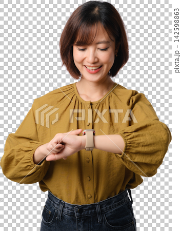 Smiling Asian woman checking smartwatch on her wrist while wearing mustard blouse and standing against transparent background Smiling Asian woman checking smartwatch on her wrist while wearing mustard blouse and standing against transparent background 142598863